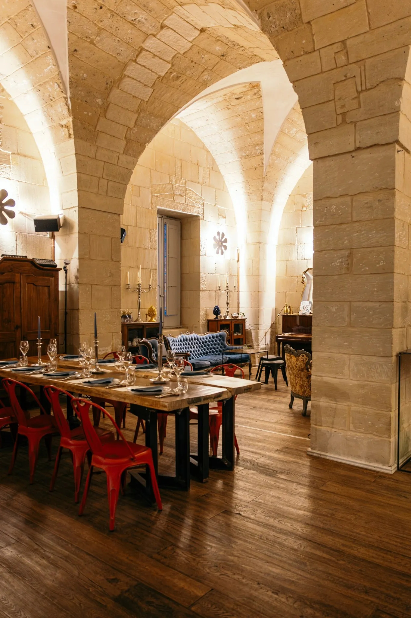 La sala a volte di Palazzo Mandurino con la tavola apparecchiata: piano di legno massello, sedie rosse, calici e candele.