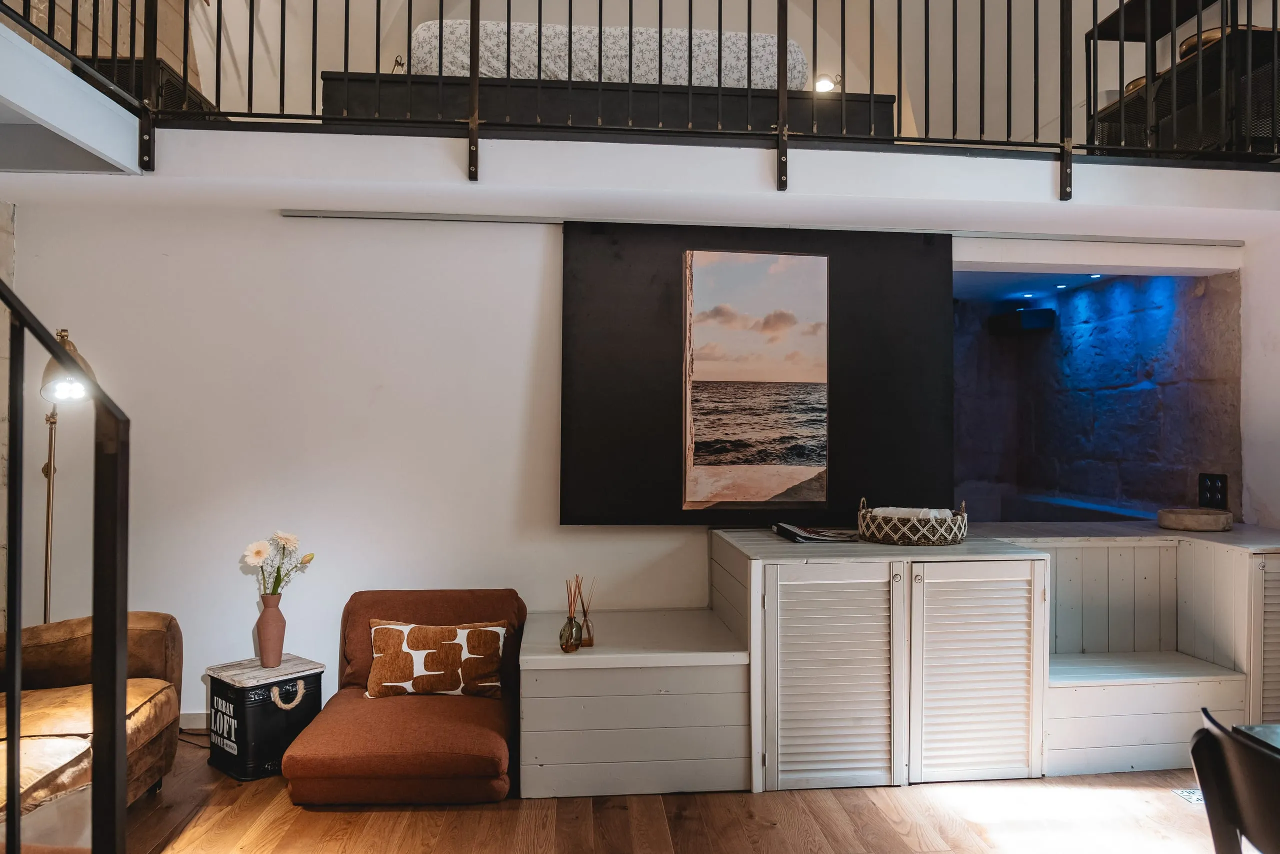 Lu Rusciu te lu Mare: il salotto con le poltroncine di cuoio sotto un quadro di mare, e dietro la parete la mini piscina illuminata di blu.