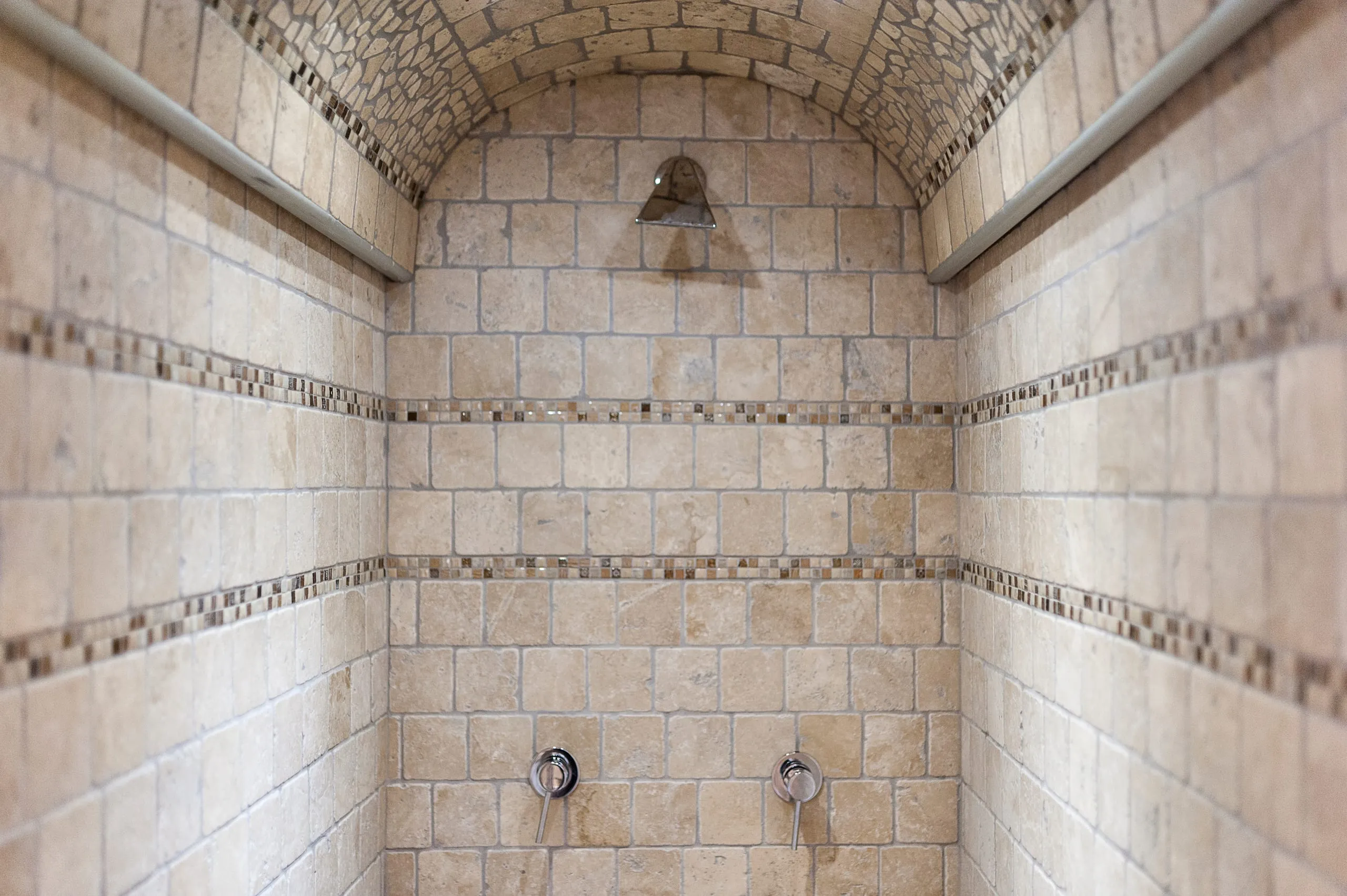 Il bagno turco della suite Sikalindi: la nicchia a volta rivestita di piastrelle chiare con la fascia decorata e i comandi della doccia.