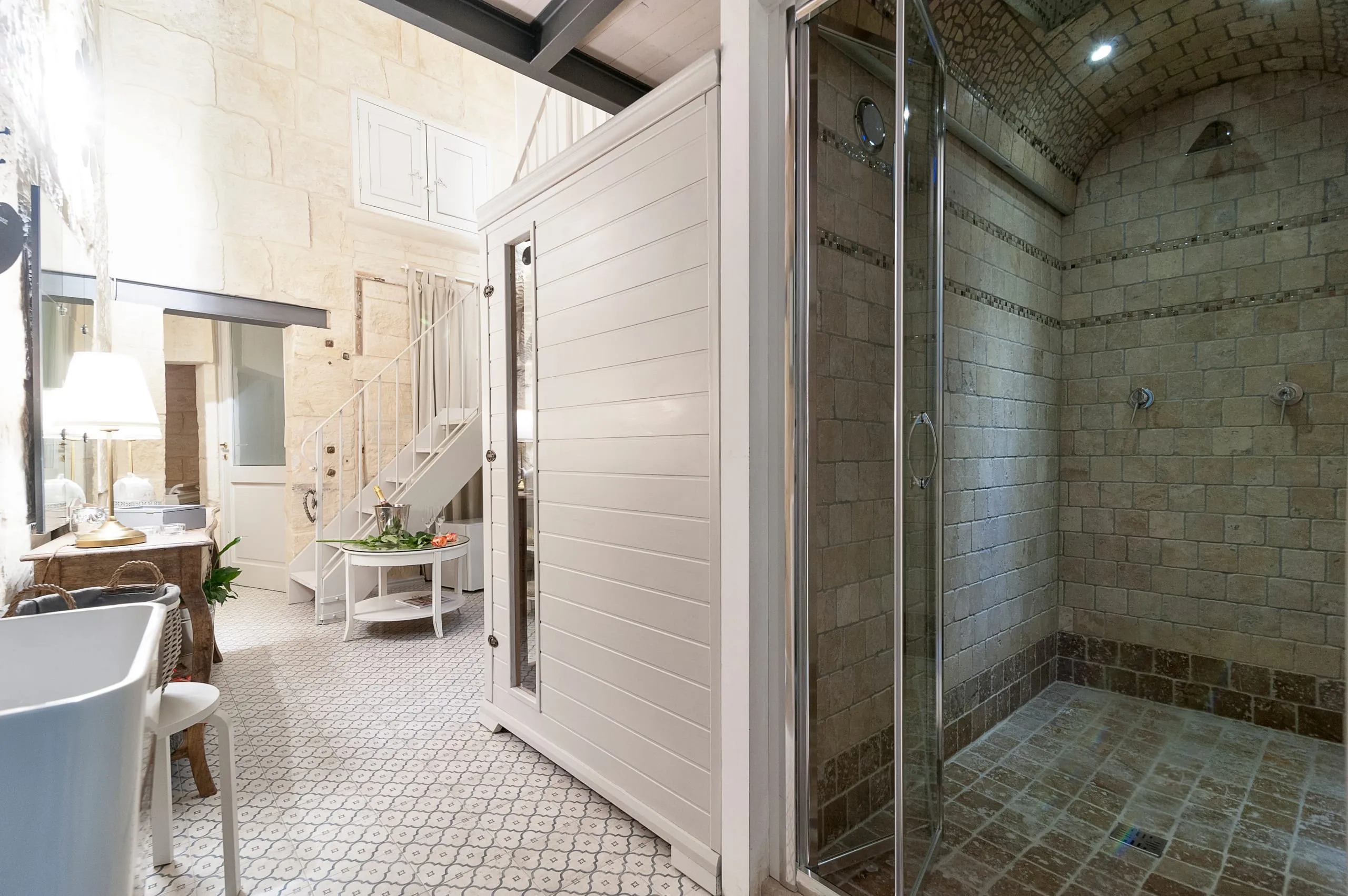 Sikalindi: il bagno turco in pietra a mosaico accanto alla cabina della sauna, e sullo sfondo la vasca e il salotto.
